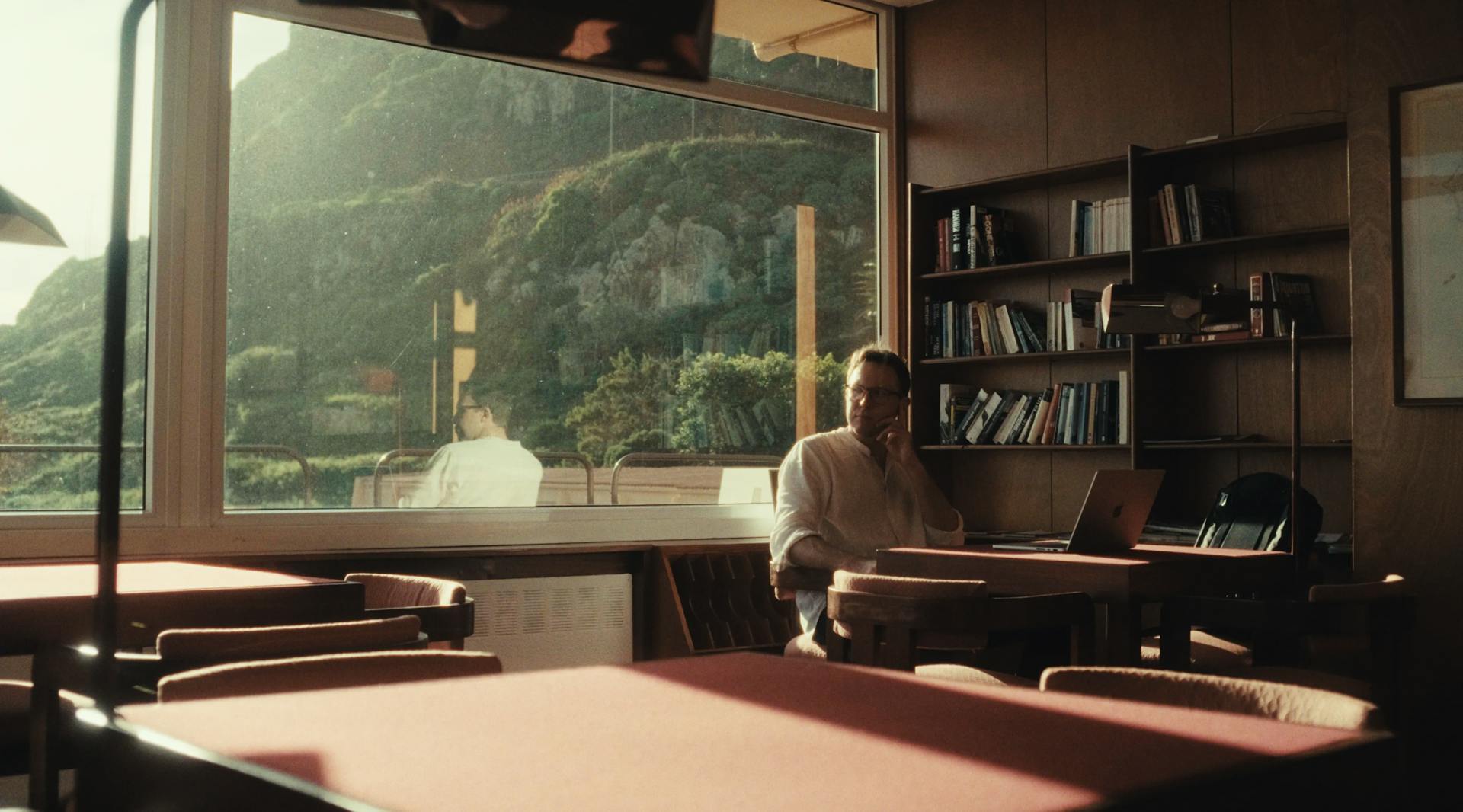 a man sitting at a table in front of a window