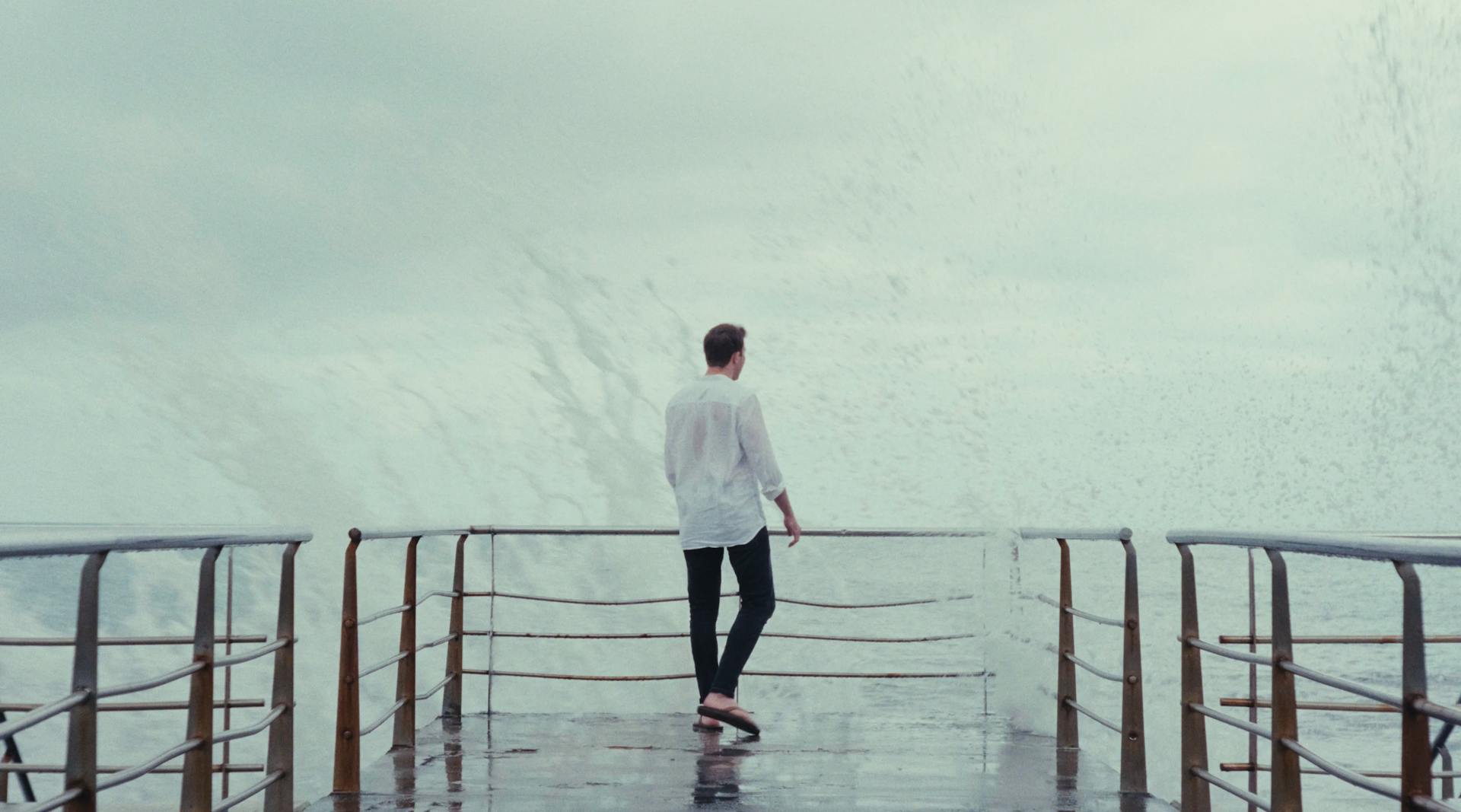 a man standing on a deck of a ship in the rain