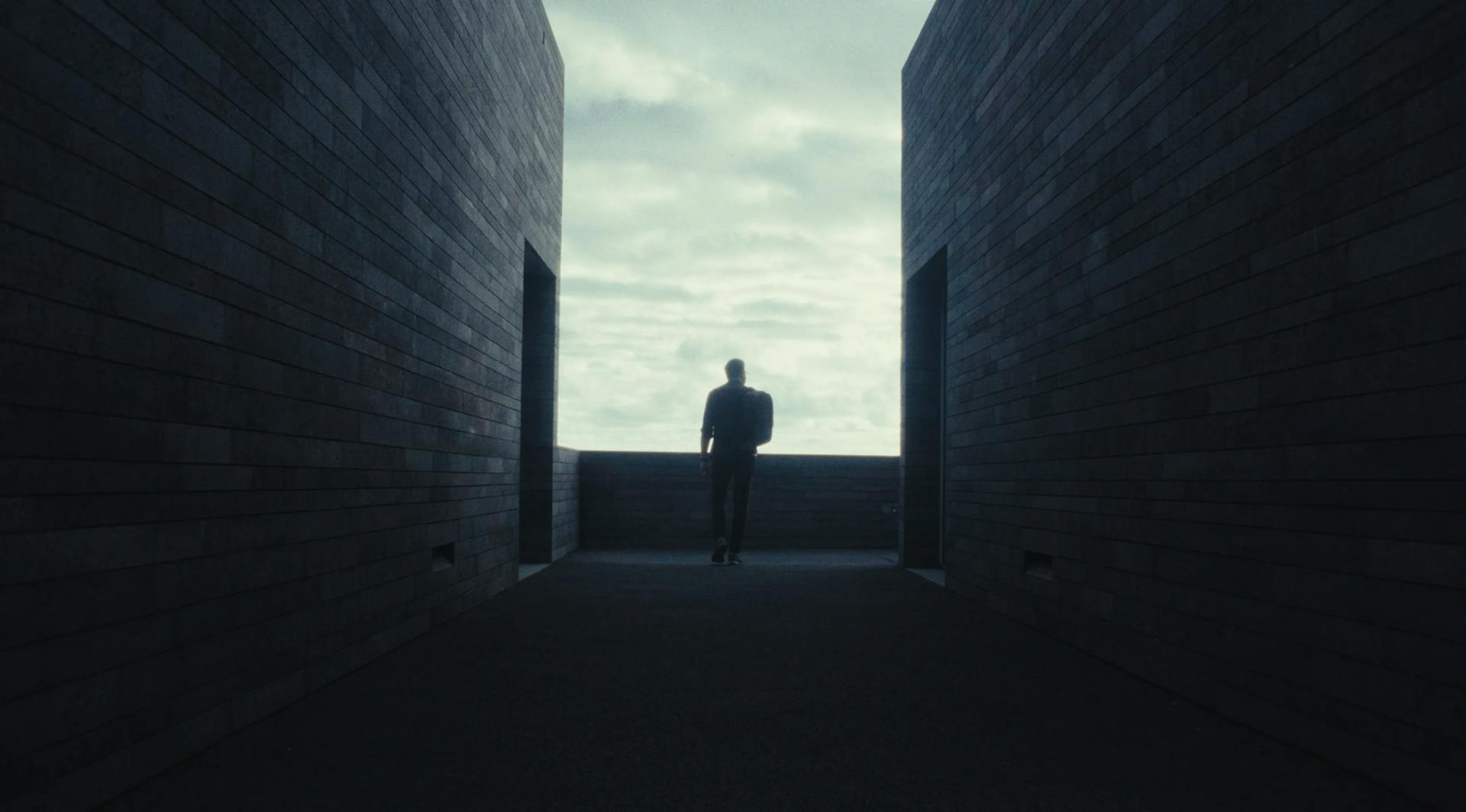 a man standing in a dark alley between two buildings