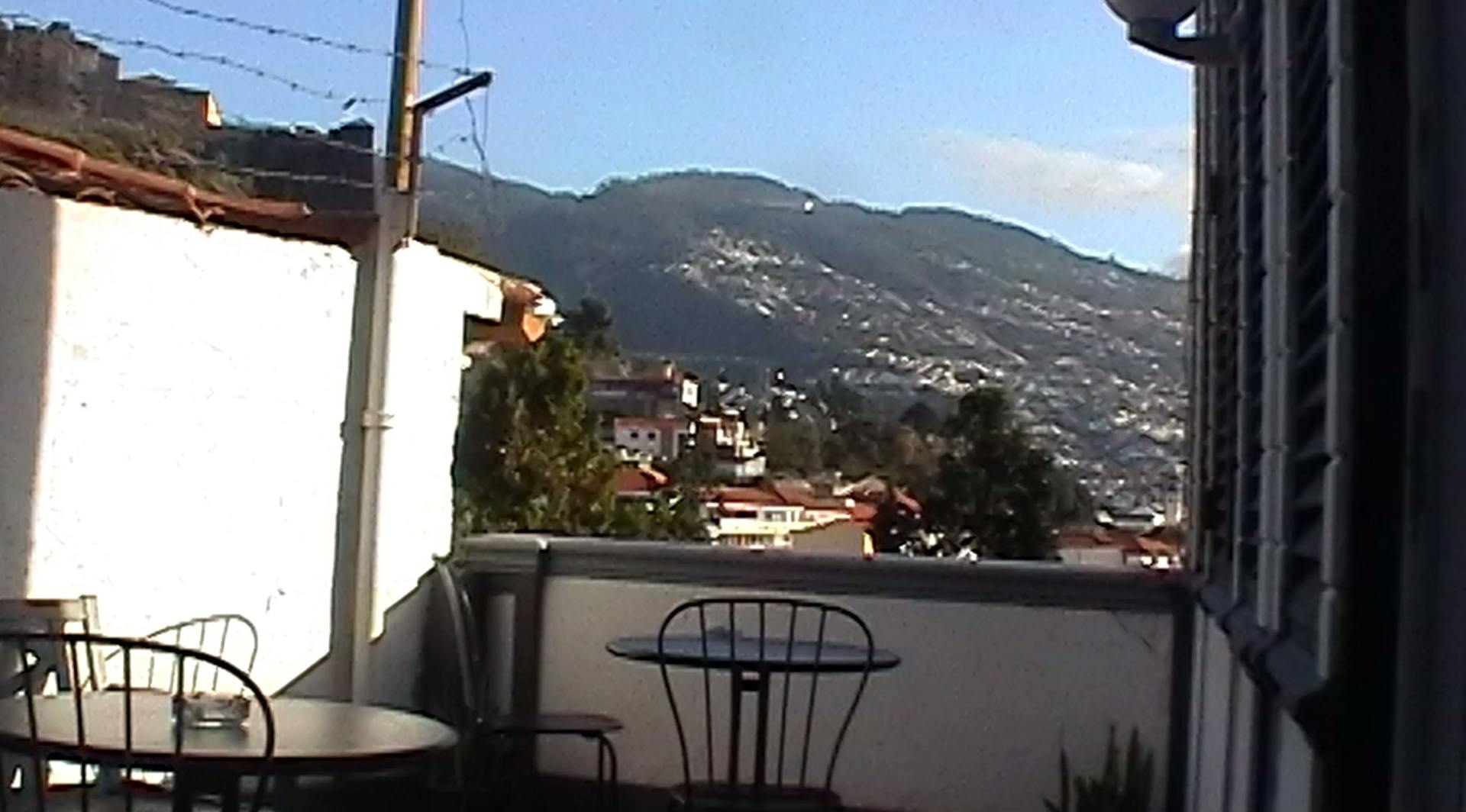 a balcony with a table and chairs and mountains in the background