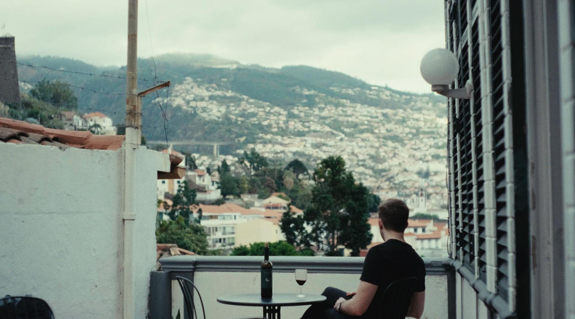 a man sitting at a table on a balcony