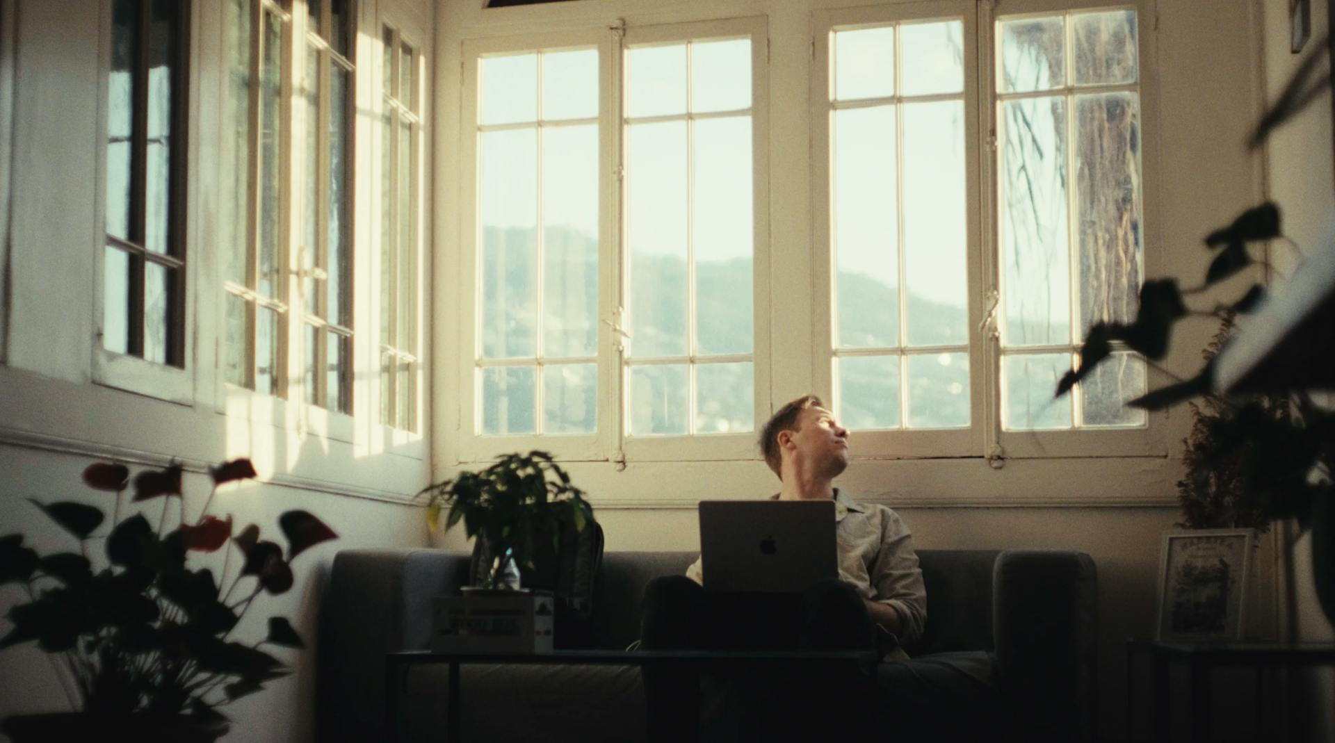 a man sitting on a couch in front of a window