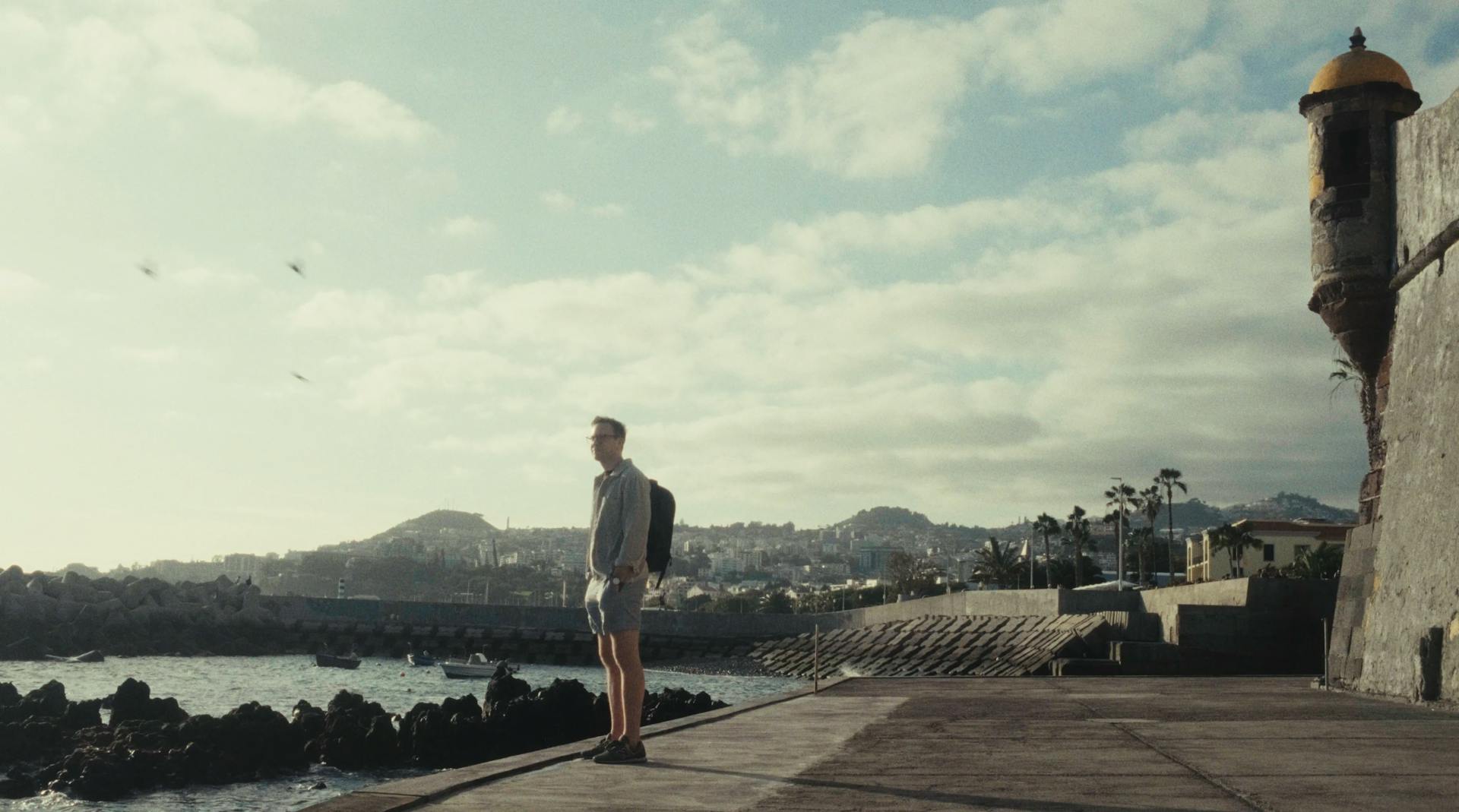 a man standing on a pier next to a body of water