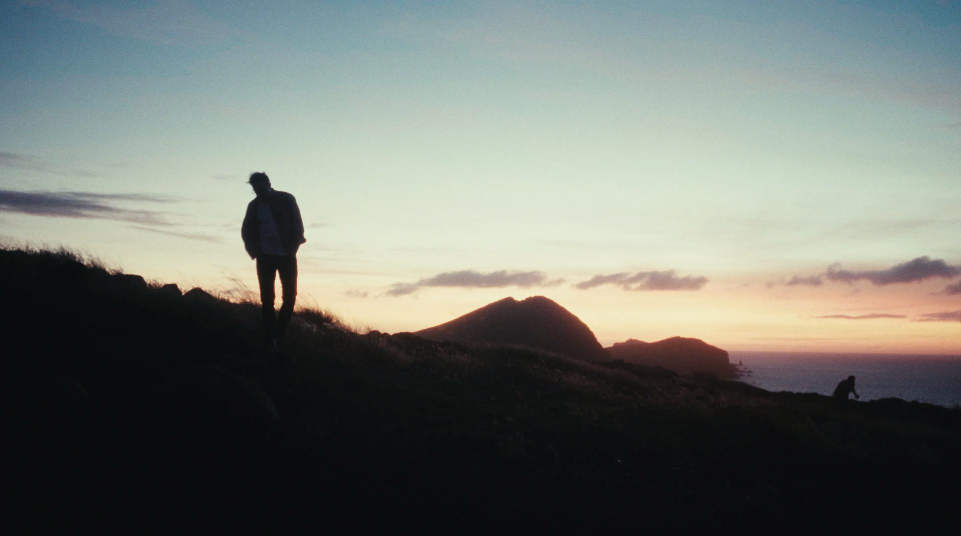 a man standing on top of a hill at sunset