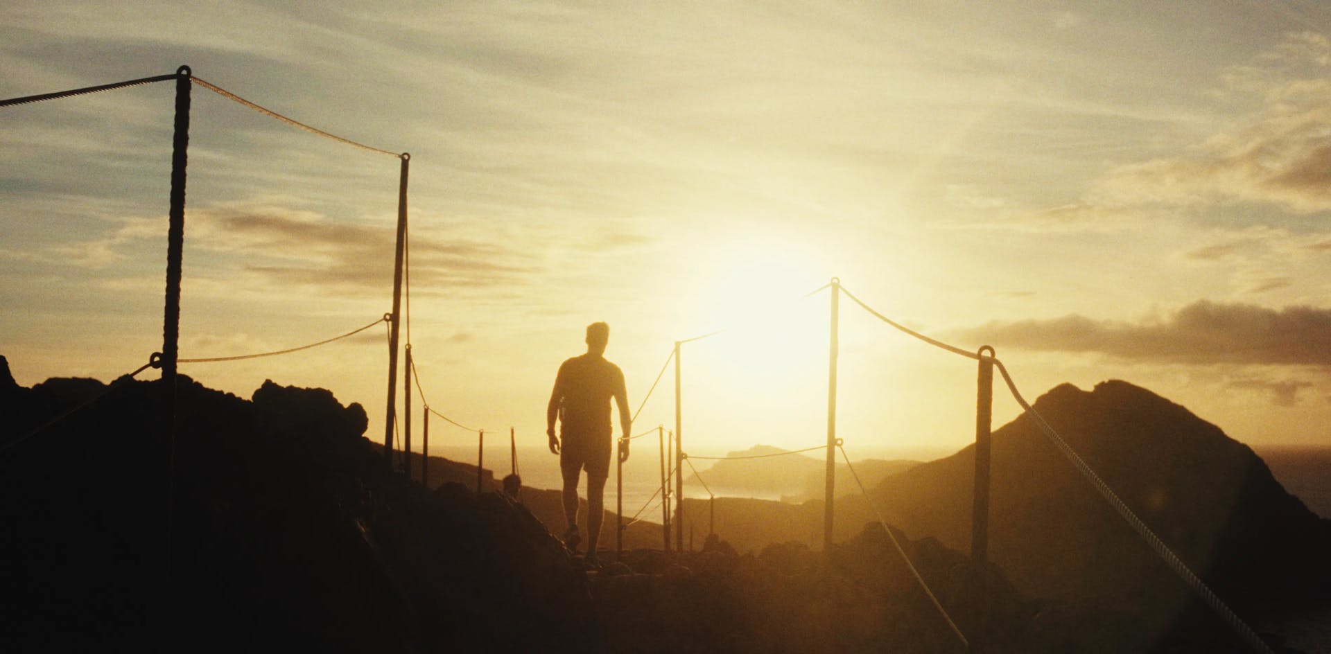 a man standing on top of a mountain at sunset