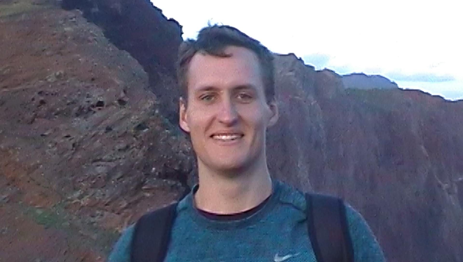 a man with a backpack standing in front of a mountain