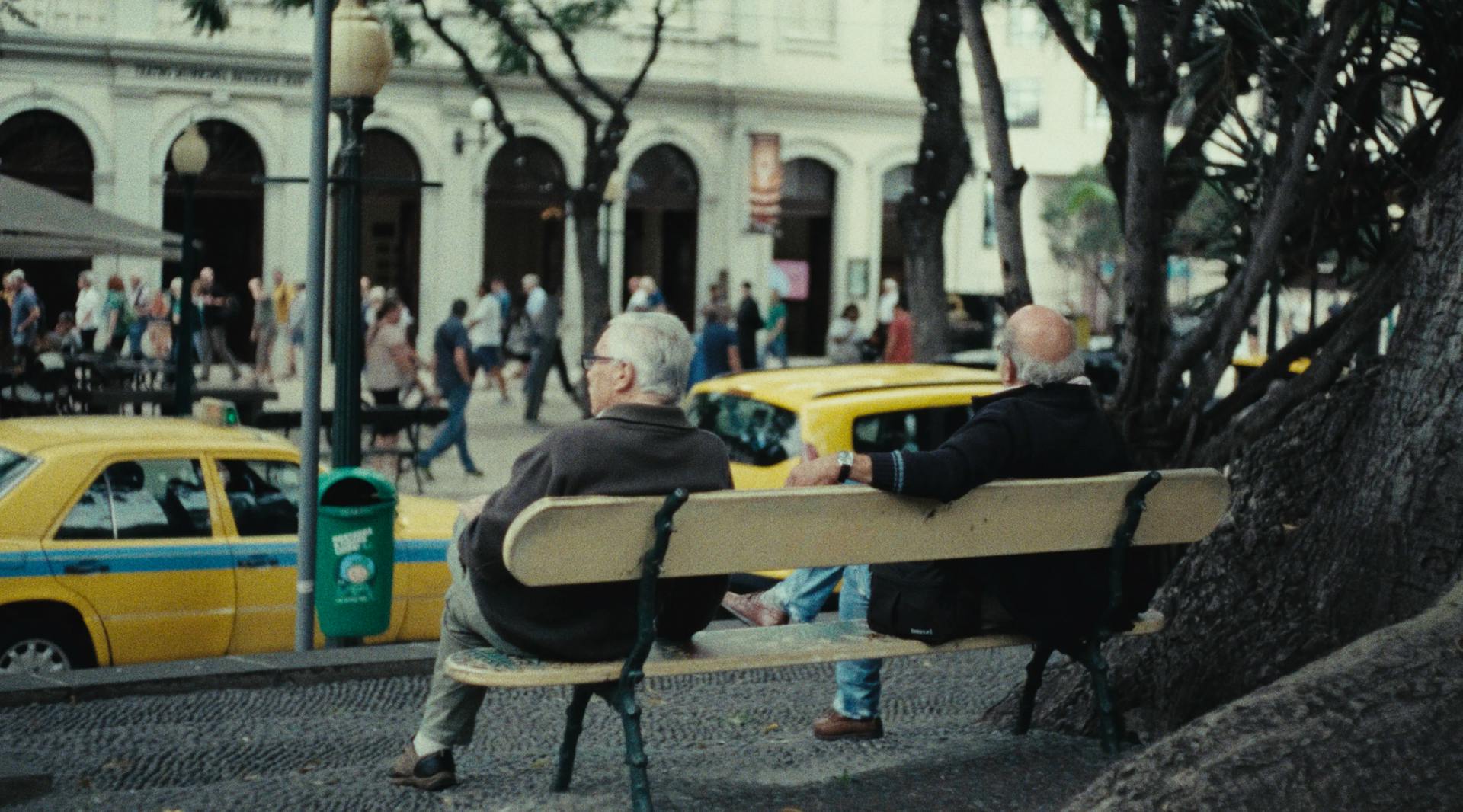 a couple of men sitting on top of a wooden bench