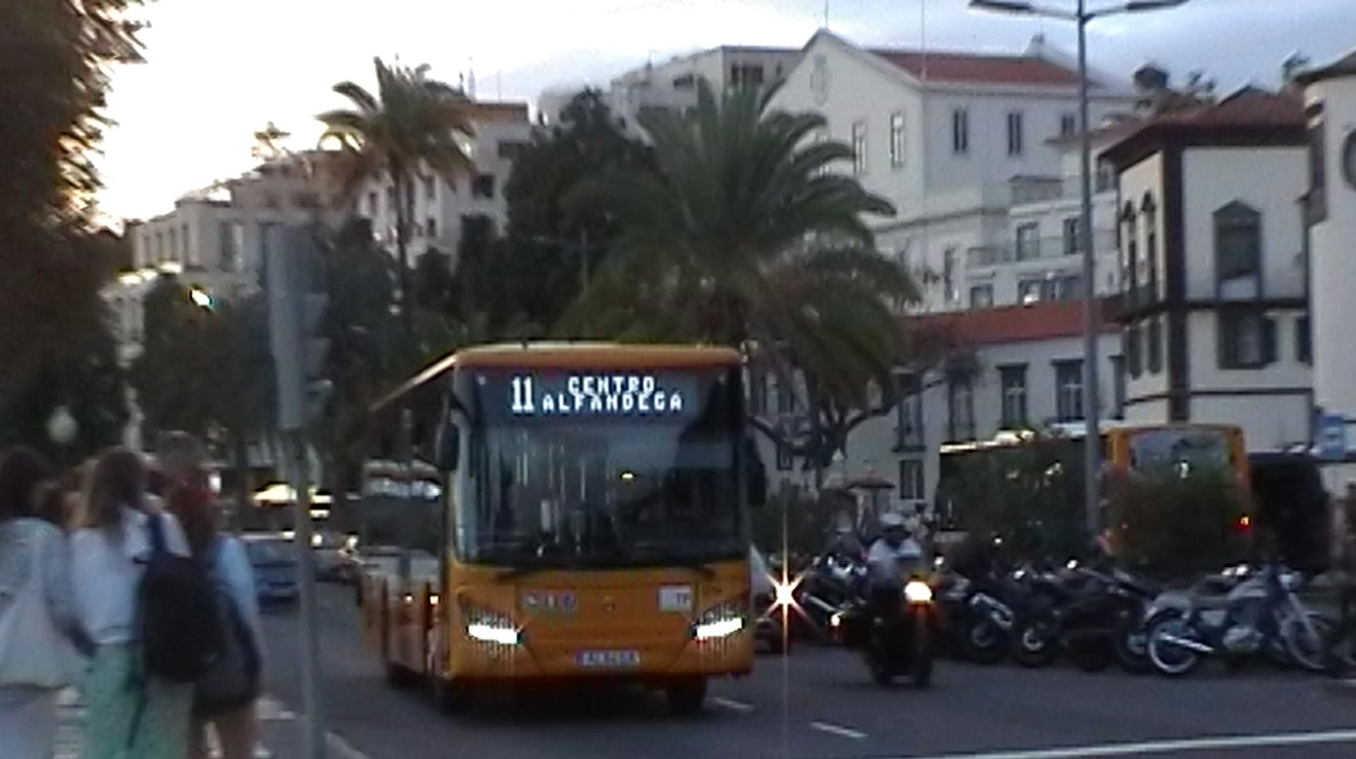 a yellow bus driving down a street next to tall buildings