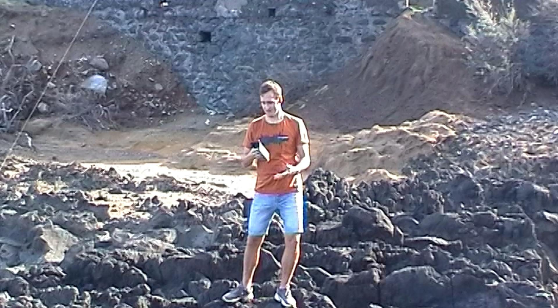 a man standing on a rocky area with a frisbee in his hand