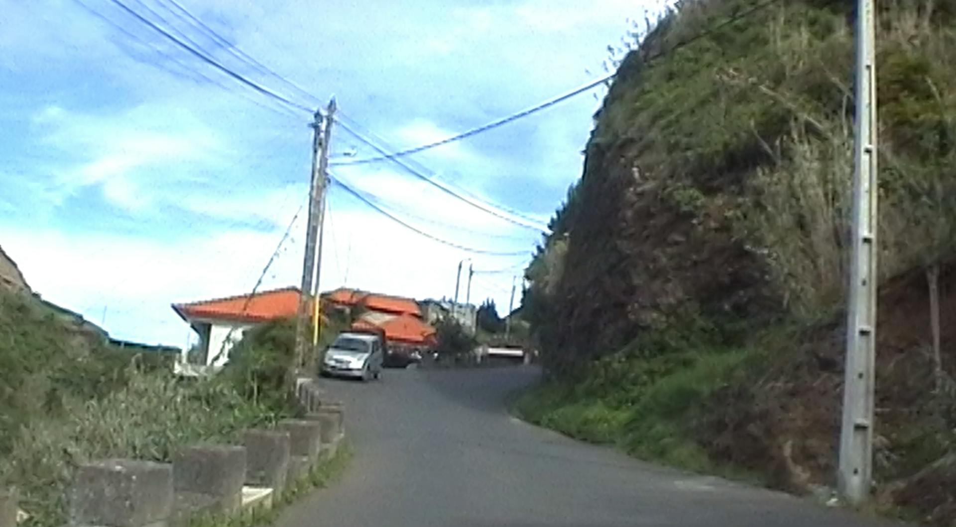 a car driving down a road next to a lush green hillside