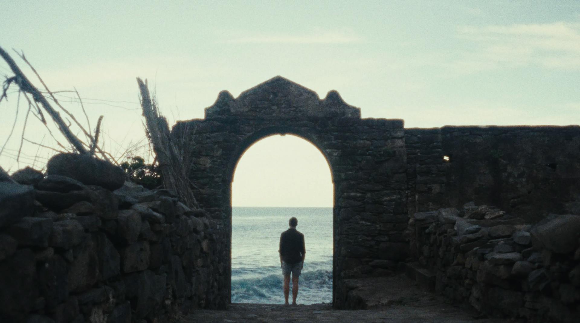 a person standing at the end of a tunnel by the ocean