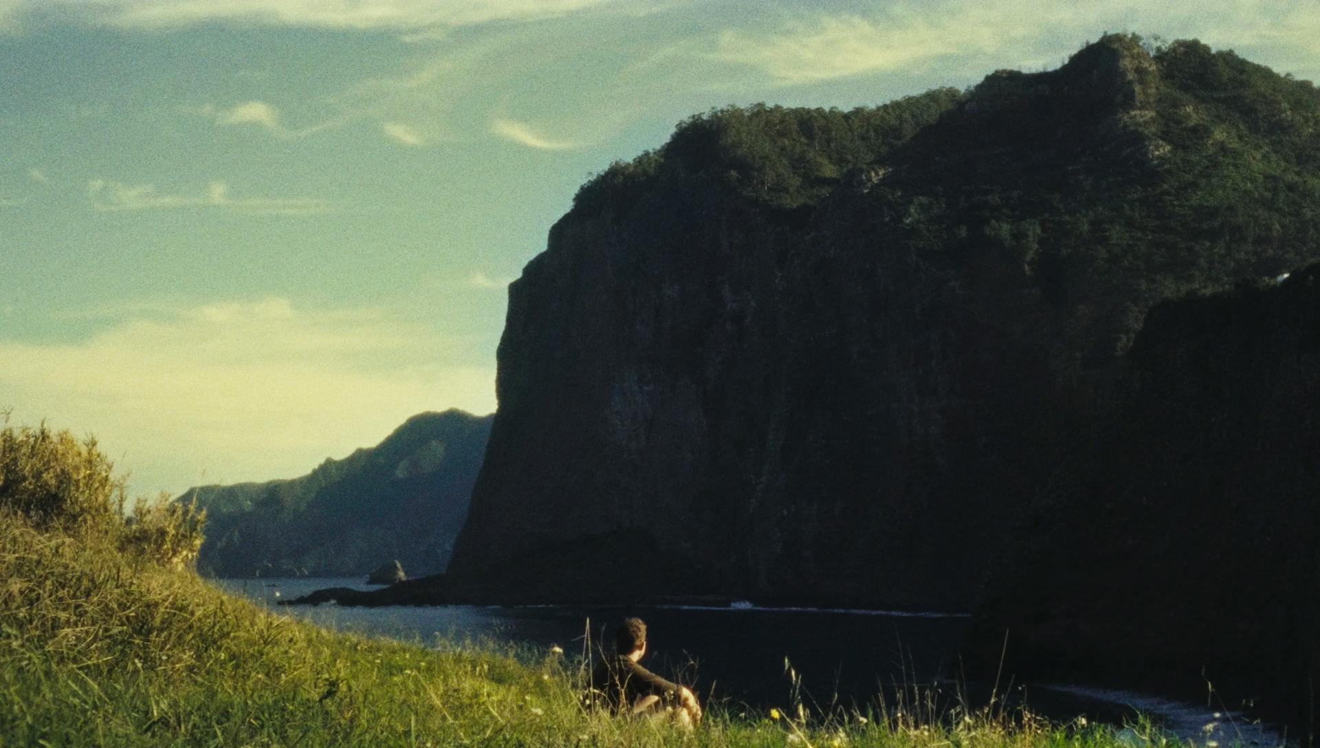 a person sitting on a hill overlooking a body of water