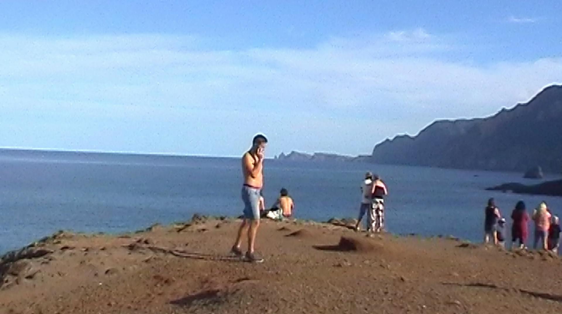 a group of people standing on top of a hill next to a body of water