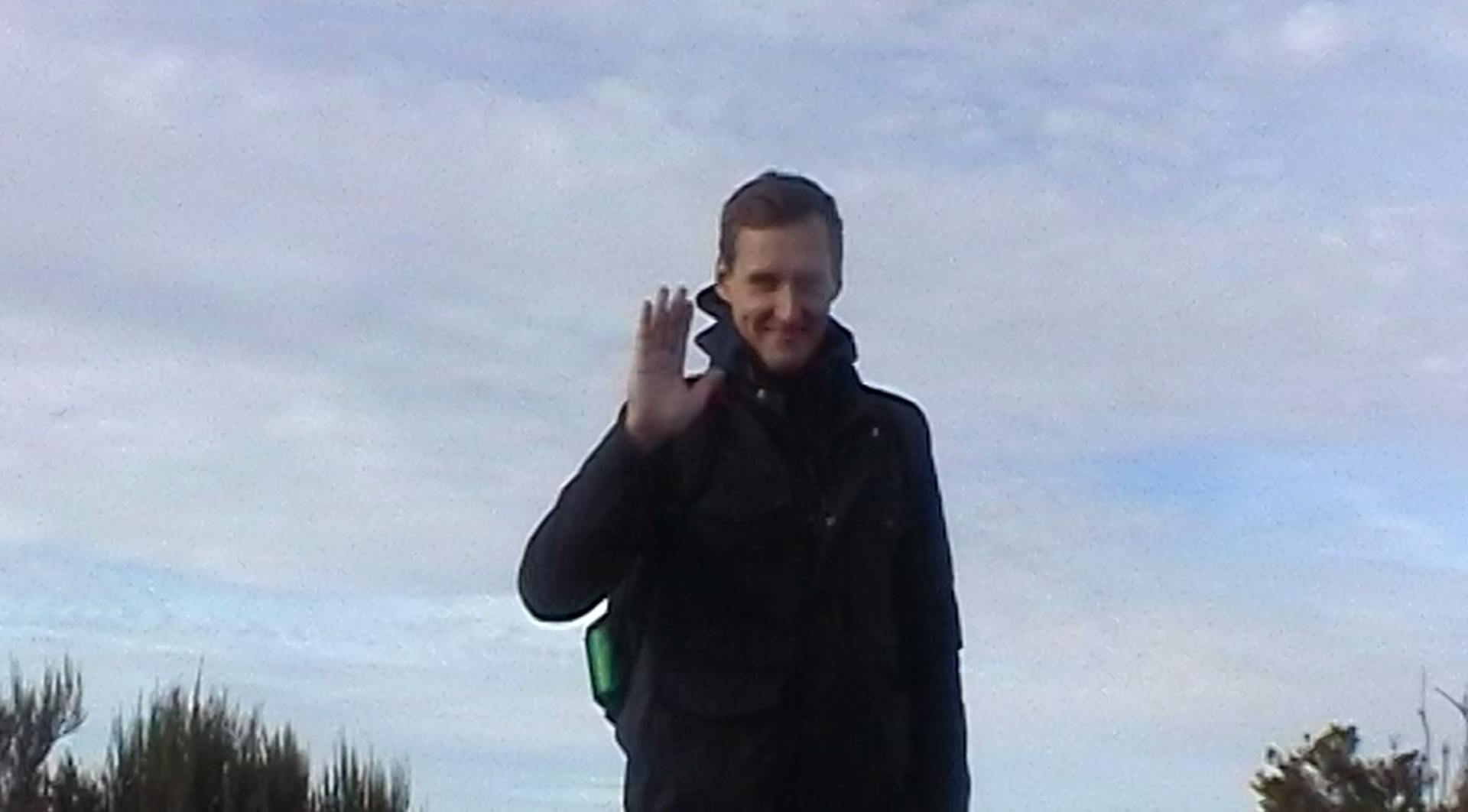 a man standing in a field with a cell phone to his ear