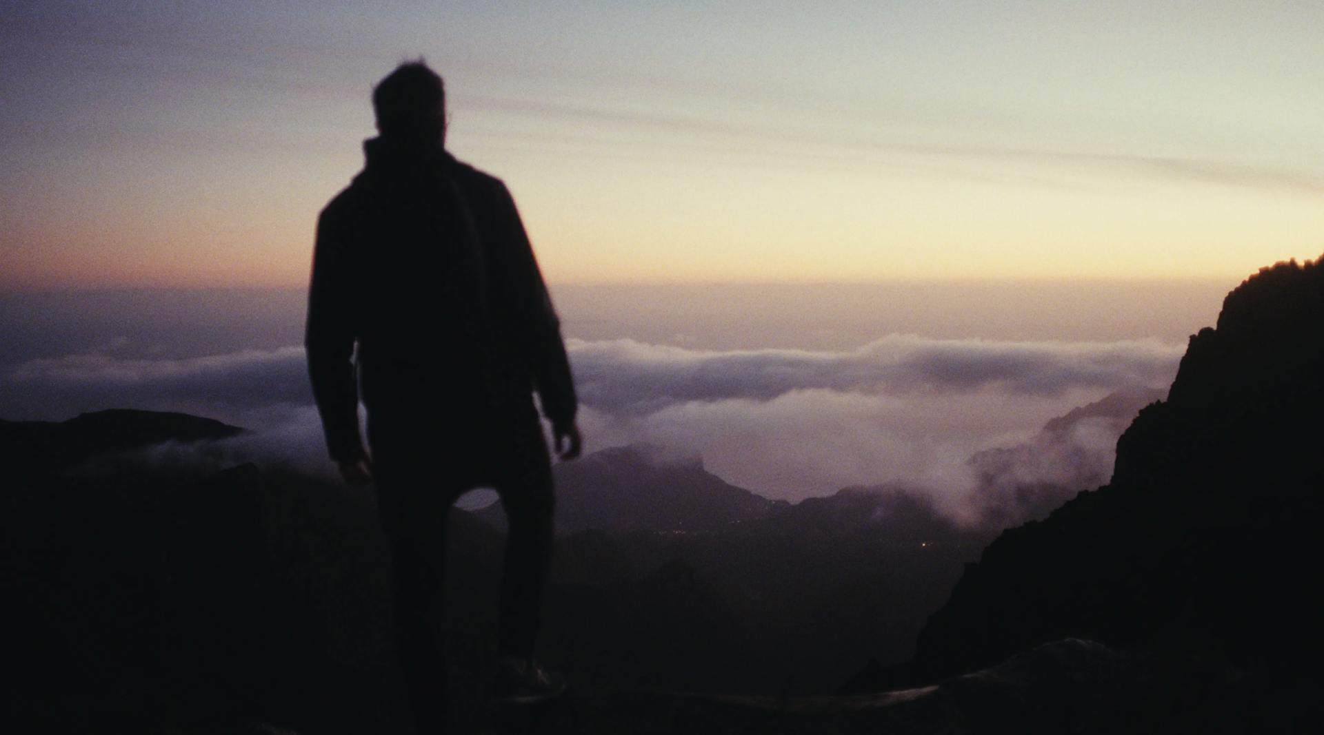 a man standing on top of a mountain at sunset