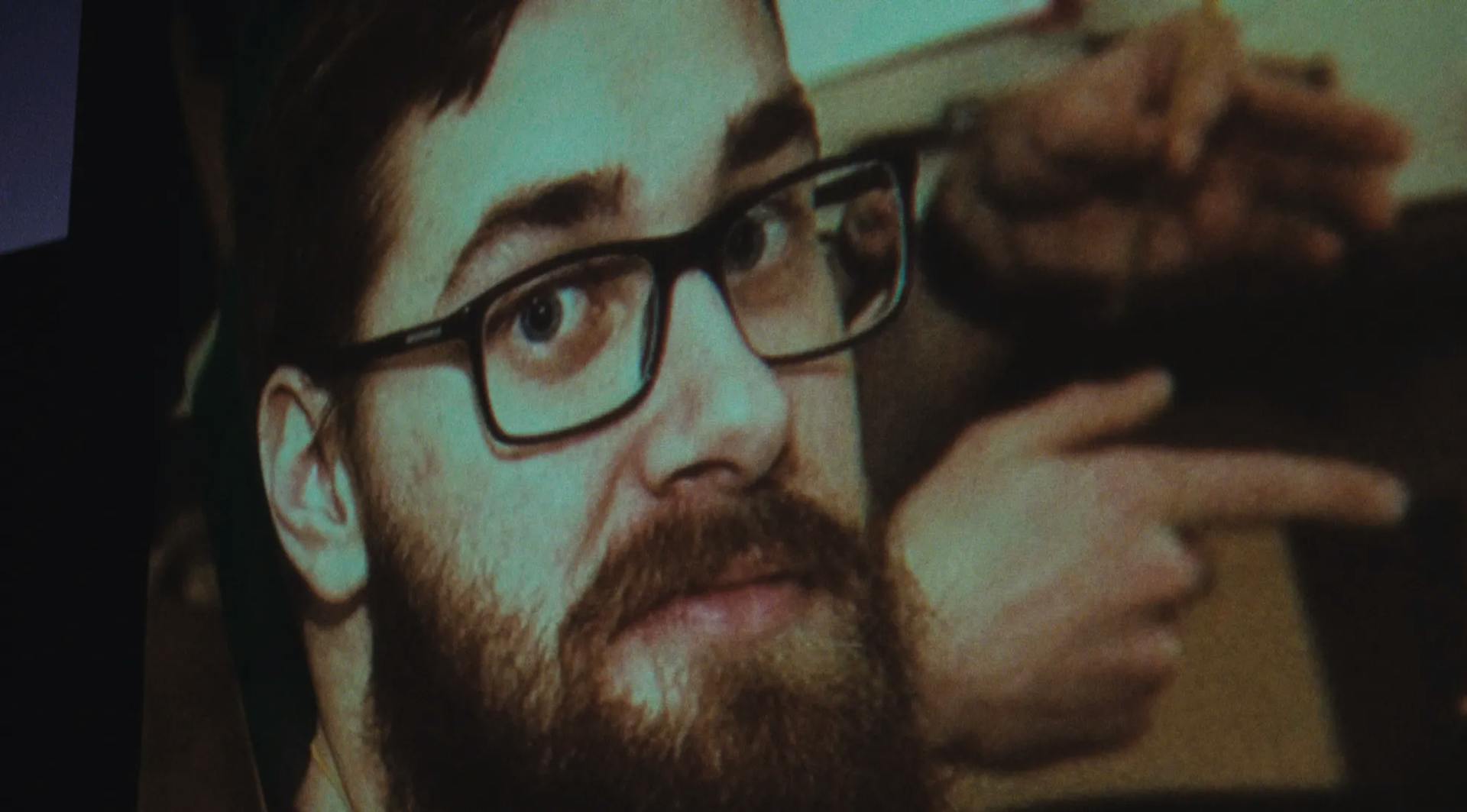 a man with a beard and glasses is staring at something