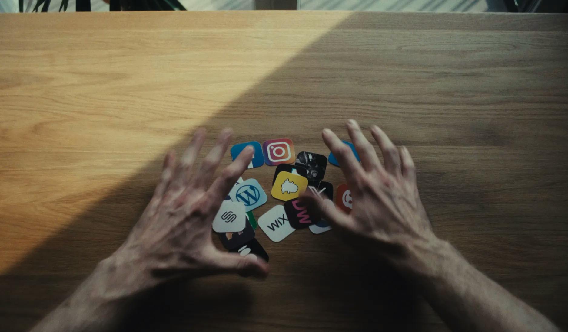 a person's hands reaching for a pile of social media icons