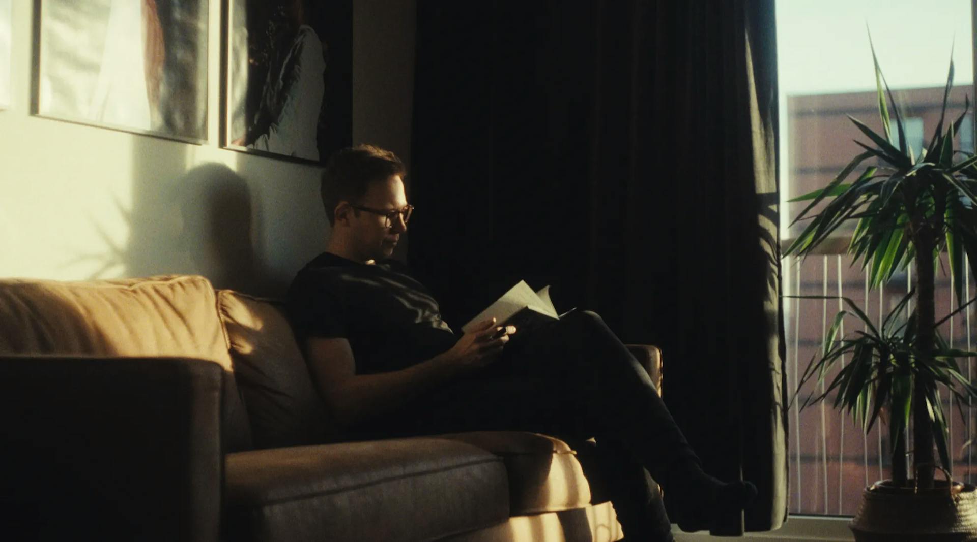 a man sitting on a couch reading a book